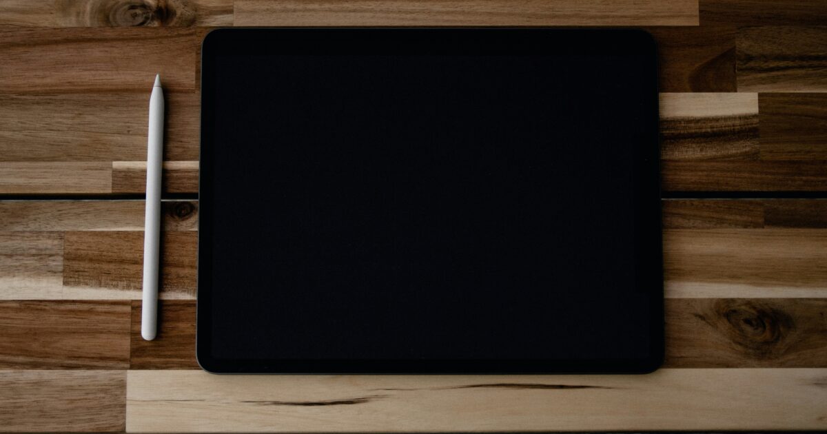 木製テーブルに置かれた黒いタブレットと白いスタイラスペン