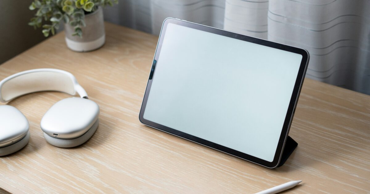木製デスクに置かれたタブレットとヘッドホンとスタイラスペン