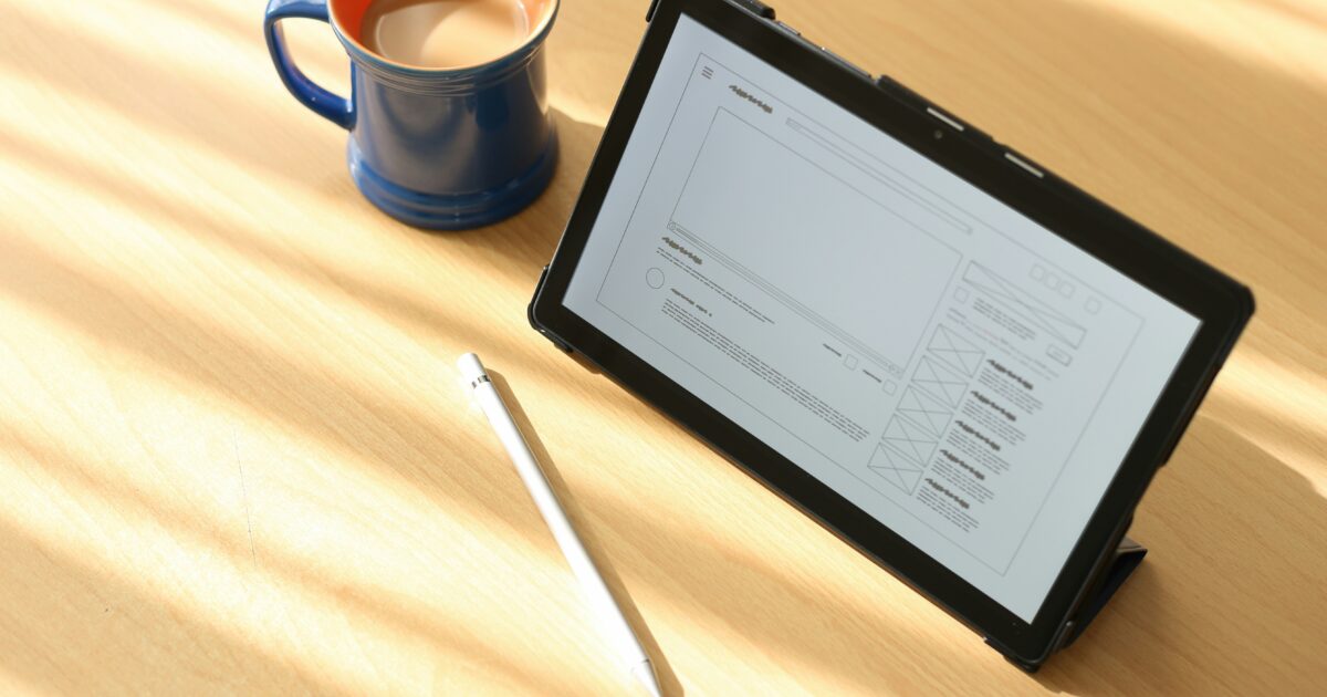 コーヒーカップとワイヤーフレーム設計中のタブレットとスタイラスペン
