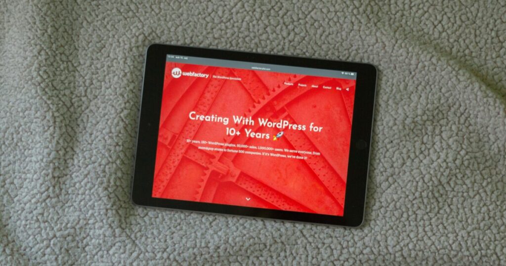 カーペットの上に置かれたWordPressのサイトを表示するタブレット