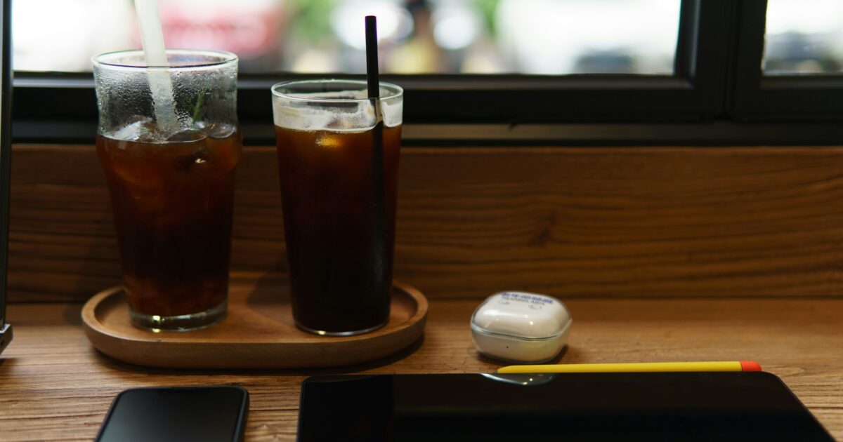 カフェのカウンターに置かれたタブレットとアイスコーヒーと補聴器