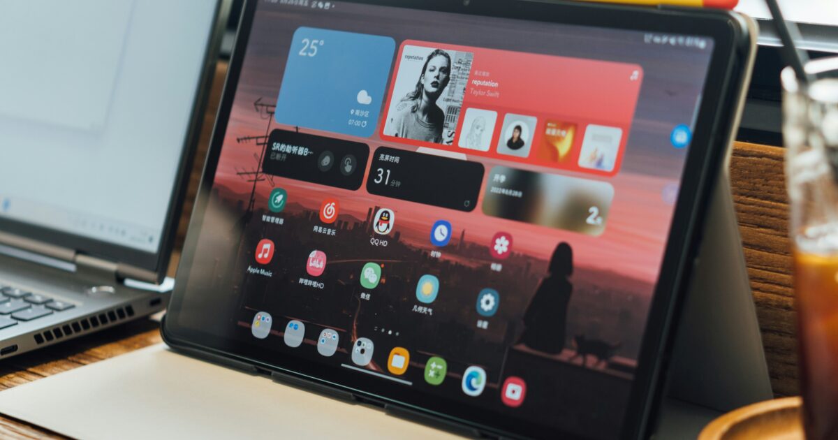 アプリ画面を表示したタブレットとノートパソコンとアイスコーヒー