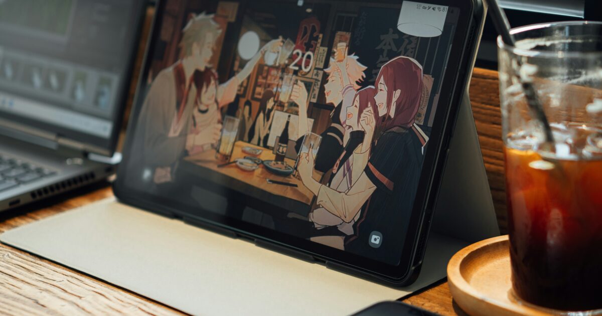 アニメ画像を表示したタブレットとカフェのテーブルに置かれた飲み物